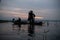 Silhouette of fisherman at sunrise, Standing aboard a rowing boat and casting a net to catch fish