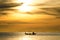 Silhouette of fishermen in the boat on sea with yellow and orange sun in the background