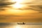Silhouette of fishermen in the boat on sea with yellow and orange sun in the background