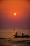 Silhouette of Fishermen coming back by boat to sea beach during early morning Sunrise time from the ocean.