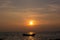 Silhouette of a fishing boat in the middle of the picture, in the evening there is a sunset at the sea