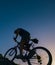 Silhouette of a fit male mountain biker riding his bike uphill on rocky harsh terrain on a sunset