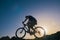 Silhouette of a fit male mountain biker riding his bike uphill on rocky harsh terrain on a sunset