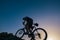 Silhouette of a fit male mountain biker riding his bike uphill on rocky harsh terrain on a sunset