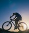 Silhouette of a fit male mountain biker riding his bike uphill on rocky harsh terrain on a sunset