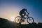 Silhouette of a fit male mountain biker riding his bike uphill on rocky harsh terrain on a sunset