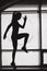 Silhouette of fit woman jump in front of big window in studio. Athletic woman have exercise in gym