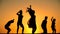 Silhouette of five kids jumping against sunset