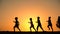 Silhouette of five kids running against sunset