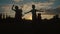 The silhouette of five little children having fun and dancing in the field during the sunset.