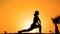 Silhouette of flexible female practicing yoga on mountain top at sunset, sport