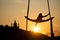 Silhouette of a flexible woman acrobat on aerial silk during a sunset on Kiev city background. concept of freedom and