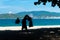 Silhouette of food delivery man on beach in asian hat and an amusement park on background