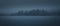 Silhouette of a forested island in the fog. Panoramic image