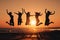 Silhouette of friends jumping by the beach at sunset.