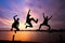 Silhouette of friends jumping over the lake on sunrise background, happy life, winning and achievement concept