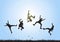 Silhouette of friends jumping over meadow on blue sky background, happy life, winning and achievement concept