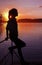 Silhouette girl background sun. Girl standing near water outdoors. Gold sunset lake. Young woman thinking about something river du