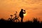 Silhouette of girl with bicycle on grass field
