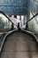 Silhouette of girl climbing airport escalators with suitcase.