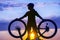 Silhouette of a girl cyclist with a Bicycle in his hands against the sunset. Sports and recreation. Hobbies and health