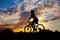 Silhouette of girl cyclist riding against the sunset