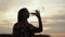 Silhouette of a girl drinks water from a plastic bottle on sunset. Woman quenches her thirst in nature.