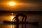 Silhouette of girl exercising yoga on SUP in the sunset on lake Velke Darko