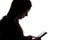 Silhouette of a girl in the hood with a tablet