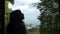 Silhouette of a girl looking out the window of a house in the forest on a seascape