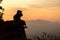 Silhouette girl photographer sitting on the rocks at high shooting at sunset.