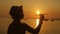 Silhouette girl plays with a toy airplane on tropical beach at sunset. Hand with small plane close up. Relax time on