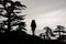 Silhouette girl in the raincoat standing with hiking backpack and sticks