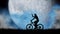 Silhouette of a girl riding a bicycle against the background of a blue moon. She raises her hand triumphantly.