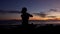 Silhouette of girl sits in namaste pose meditating by the sea at sunset.