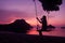 Silhouette of a girl sitting on a swing or cradle on the beach at sunset