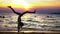 Silhouette of a girl at sunset, against the background of the sea, slender leggy girl funny doing gymnastic coups on the
