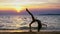 Silhouette of a girl at sunset, against the background of the sea, slender leggy girl funny doing gymnastic coups on the