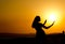 silhouette of a girl with thin waist and hands outstretched to the sun at sunset