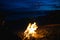 The silhouette of girl tourist around the campfire at night on the river shore