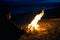 The silhouette of girl tourist around the campfire at night on the river shore