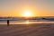 Silhouette girl watching a sunset on a sandy beach with rough ocean wind.