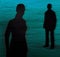 Silhouette of a girl and a young man on a blue and green textured background. Conflict, quarrel