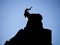 Silhouette of a goat sitting on top of a mountain.