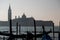 Silhouette of a gondolier rowing a gondola on the Grand Canal in Venice, with the island of San Giorgio in the background.