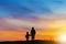 Silhouette of grandmother and grandchild looking sun down and walking on the beach evening sunset background, Happy family concept