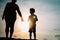 Silhouette of grandmother and grandson holding hands at sunset