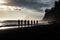 Silhouette of a group of children on the beach at sunset, Silhouettes of tourists enjoying the black sand beach and ocean waves,