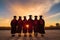 Silhouette of group of graduates in graduation gown with sunset sky background, rear perspective of a group of university