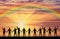 Silhouette of a group of happy people holding hands by the sea at sunset with a rainbow